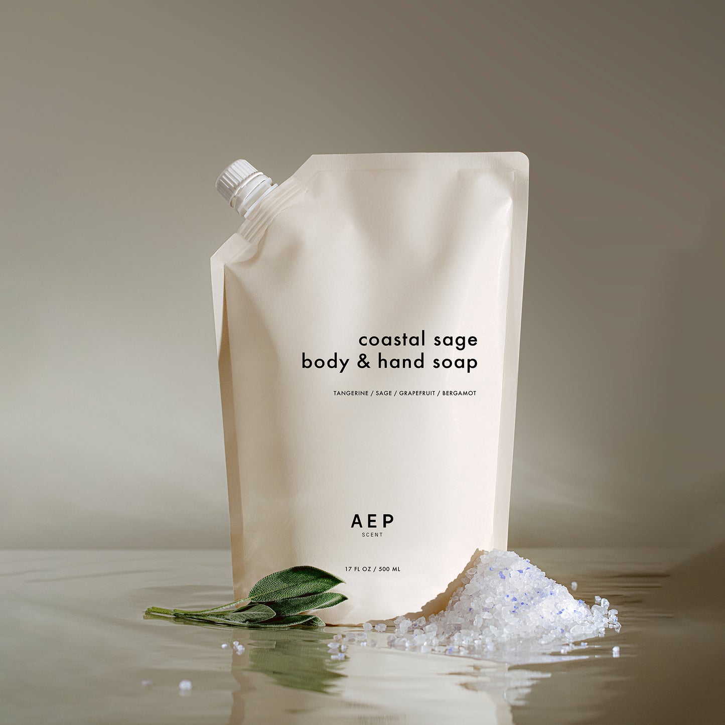 AEP Scent Coastal Sage body and hand soap refill pouch made in California, featuring notes of tangerine, sage, grapefruit, and bergamot, placed on a beige background with sea salt and sage leaves.