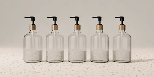 A row of clear pump bottles filled with the best refill hand soap options.