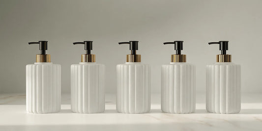 Five modern bathroom hand soap dispensers with black pumps and gold accents.