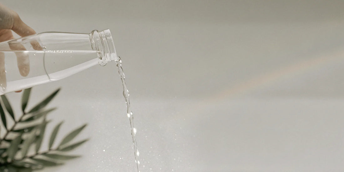 Hand pouring a bergamot hand soap refill from a bottle.