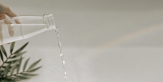 Hand pouring a bergamot hand soap refill from a bottle.