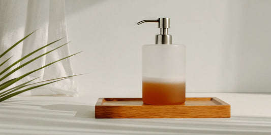 Refillable luxury soap dispenser in frosted glass on a wooden tray.