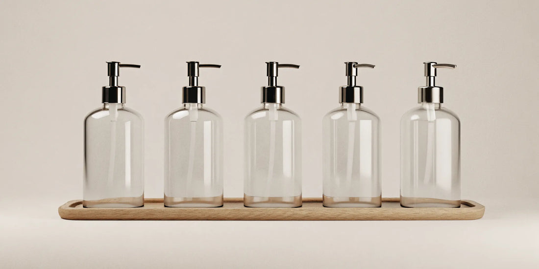 Clear soap refill bottles with pump dispensers on a tray for a chic, sustainable home.