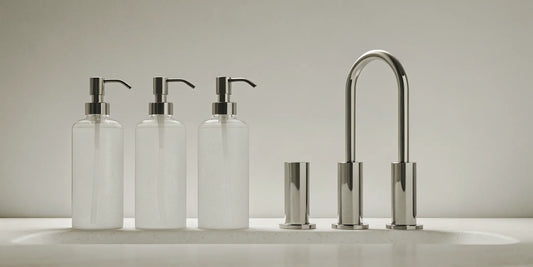 Glass soap dispensers for sink with stainless steel pumps.