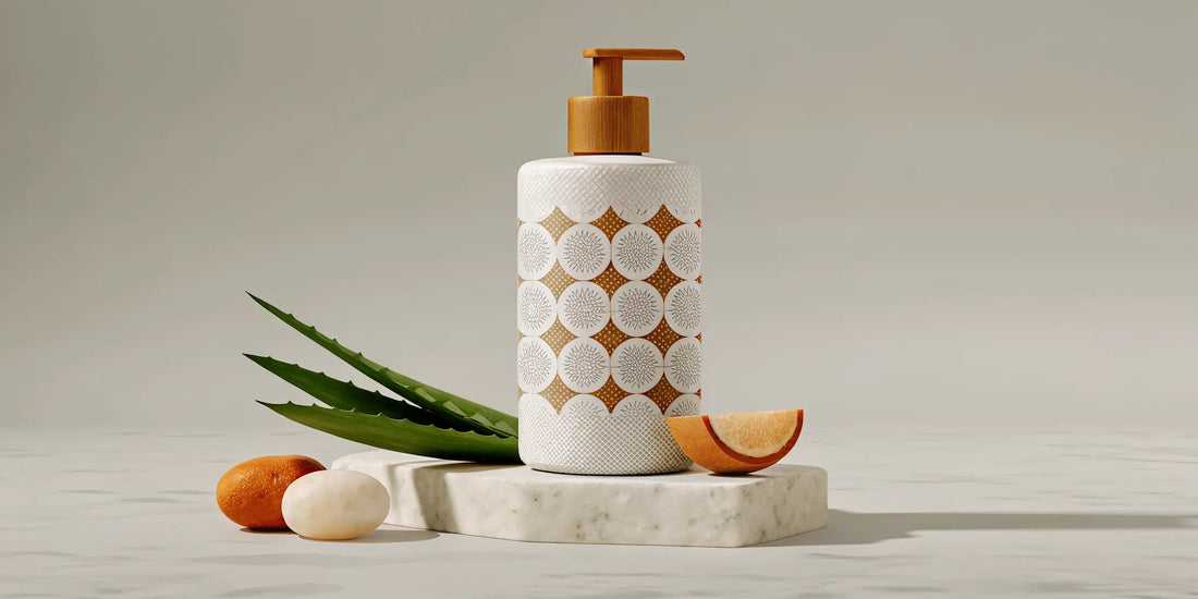 Ceramic soap dispenser with wooden pump top beside aloe leaves and natural ingredients on marble surface