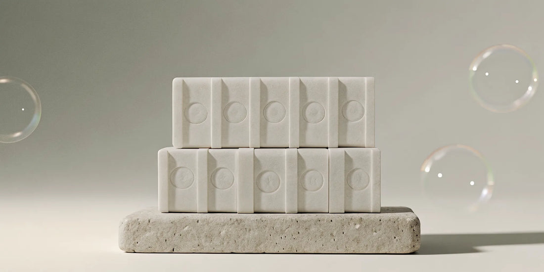 A stack of designer soap bars on a stone surface, an affordable dupe for luxury soap.