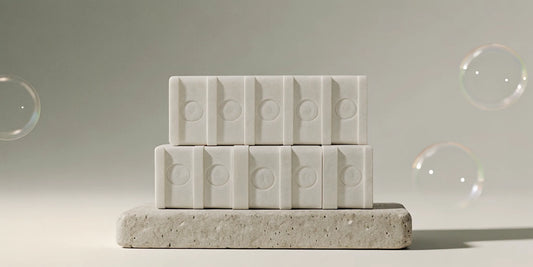 A stack of designer soap bars on a stone surface, an affordable dupe for luxury soap.
