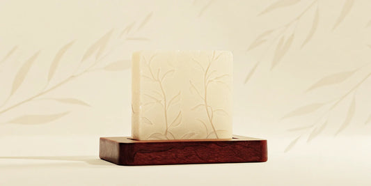 Eco-friendly hospitality soap bar with a leaf design on a wooden tray.