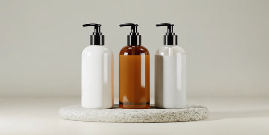 A selection of white and amber lotion bottle dispensers with pumps on a stone tray.