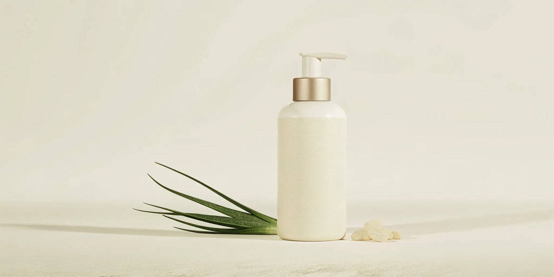 White hand soap pump bottle with aloe vera leaves and essential oils on marble countertop