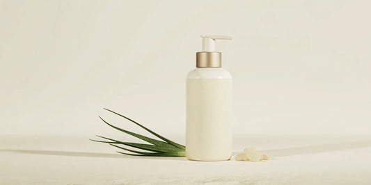 White hand soap pump bottle with aloe vera leaves and essential oils on marble countertop