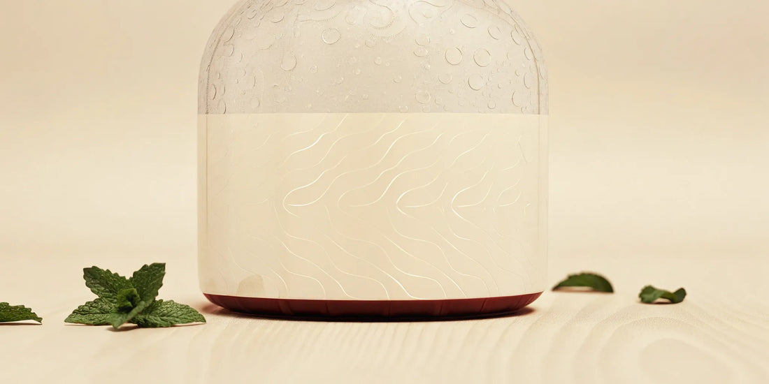 A clear bottle of mint hand soap refill next to fresh mint leaves.