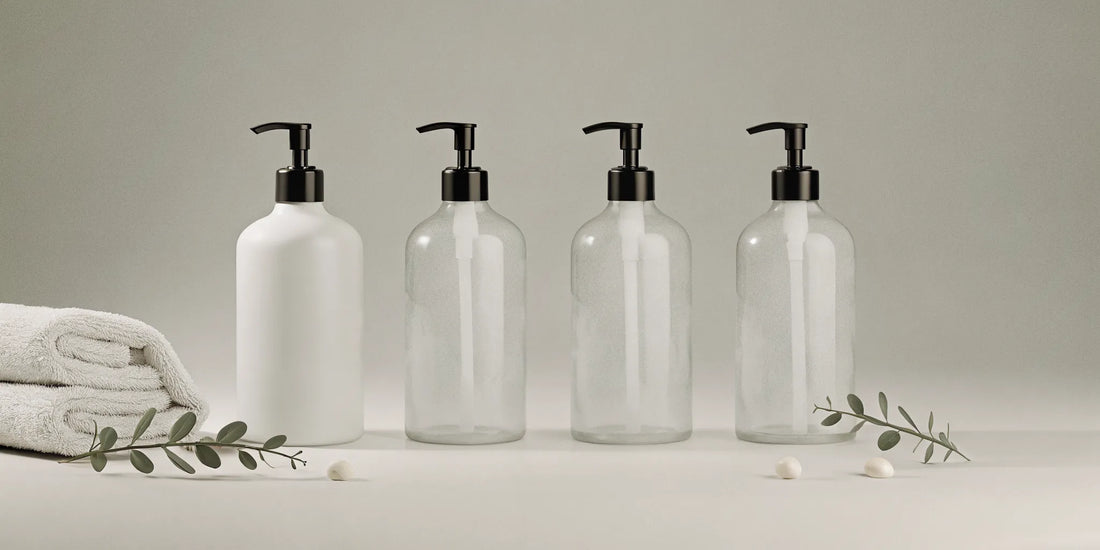 Minimalist hand wash pump bottles with black pumps, towels, and greenery.