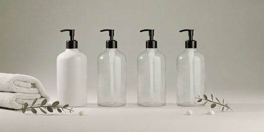 Minimalist hand wash pump bottles with black pumps, towels, and greenery.