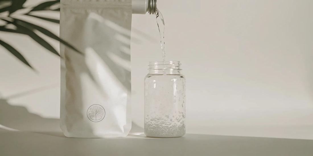 A hand pouring a zero waste soap refill into a reusable glass jar.