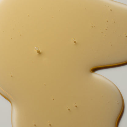 Close-up of AEP Scent Mandarin Zest hand soap texture showing a light gold, clear, bubbly gel on a beige background, highlighting the product’s natural and lightweight formula.