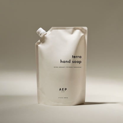 AEP Scent Terra hand soap refill pouch featuring notes of vetiver, bergamot, petitgrain, and sandalwood on a beige background.