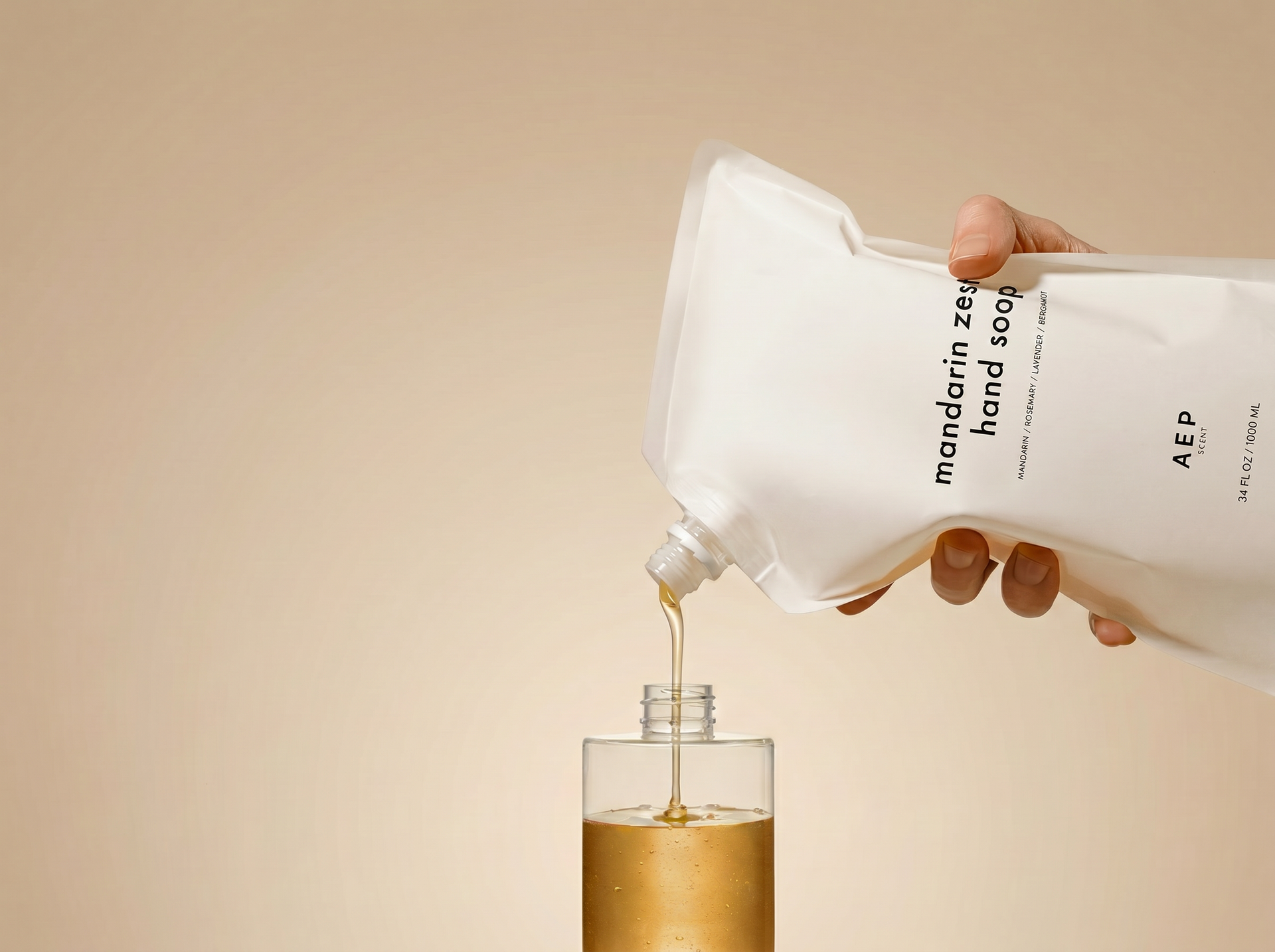 Hand pouring AEP soap from a refill pouch into a refillable bottle