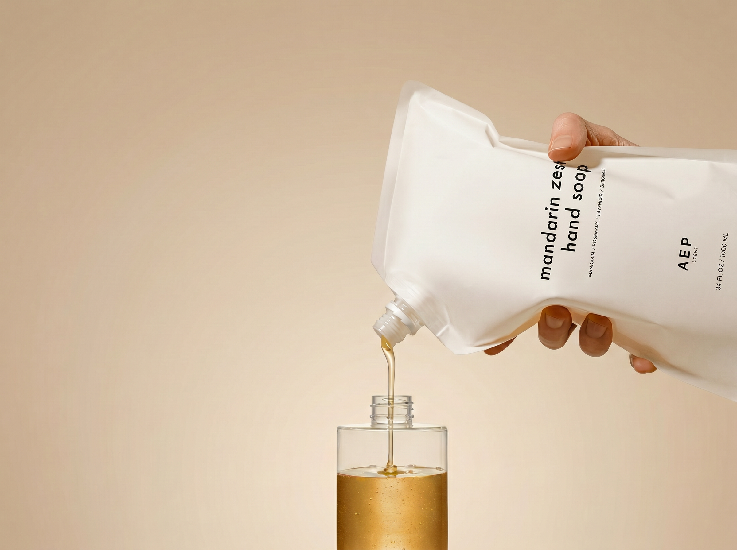 Hand pouring liquid soap from a white container labeled 'AEP' into a clear bottle against a beige background.