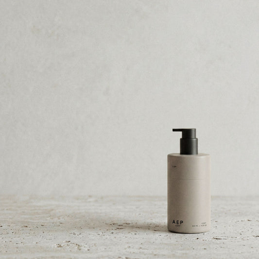 AEP Scent reusable lotion and soap dispenser bottle in matte beige with black pump, minimalist design for premium refill use, photographed on a neutral background.