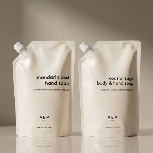 Two AEP hand and body soap pouches on a reflective surface with a neutral background. 